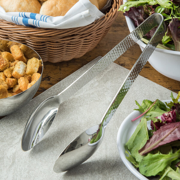 A pair of Carlisle Terra stainless steel tongs in a bowl of salad.