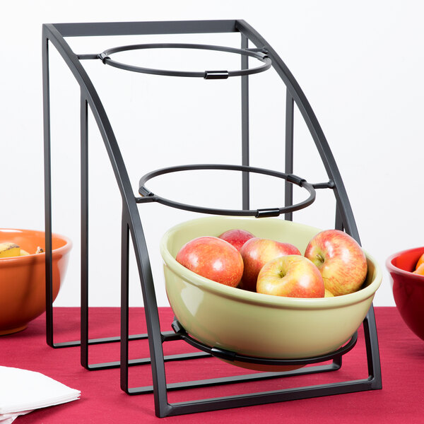 A red bowl of apples on a Cal-Mil display stand on a table.
