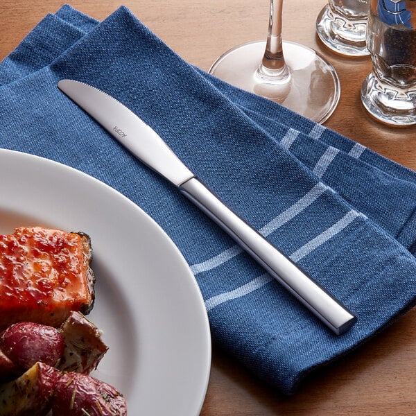 A plate of food on a napkin with an Acopa Phoenix stainless steel dinner knife.