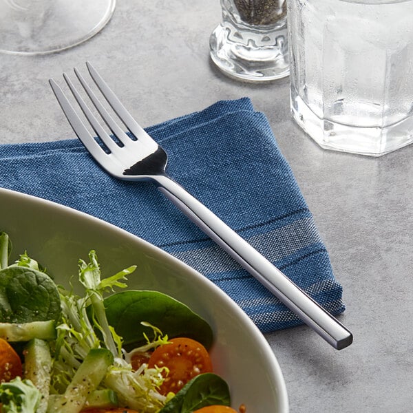 An Acopa Phoenix stainless steel salad fork next to a bowl of salad.