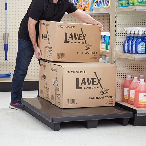 A man pushing a stack of boxes on a black plastic display base.