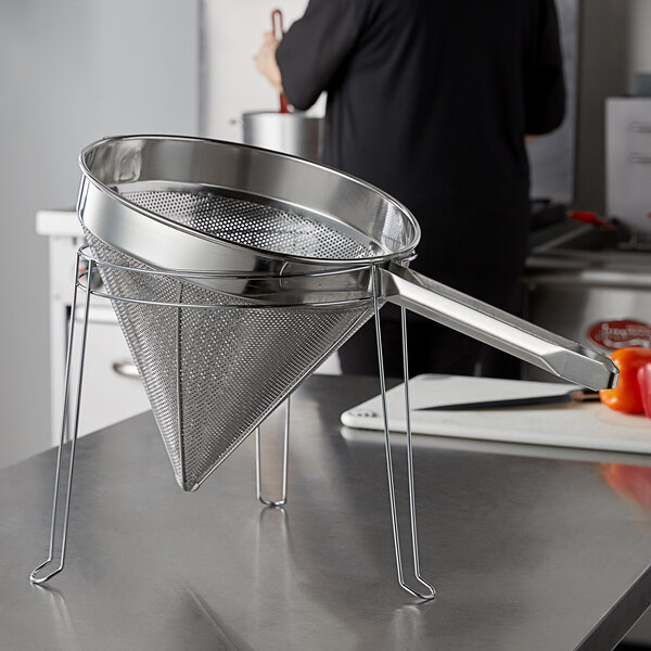 A stainless steel Choice strainer stand holding a metal sieve over a counter.