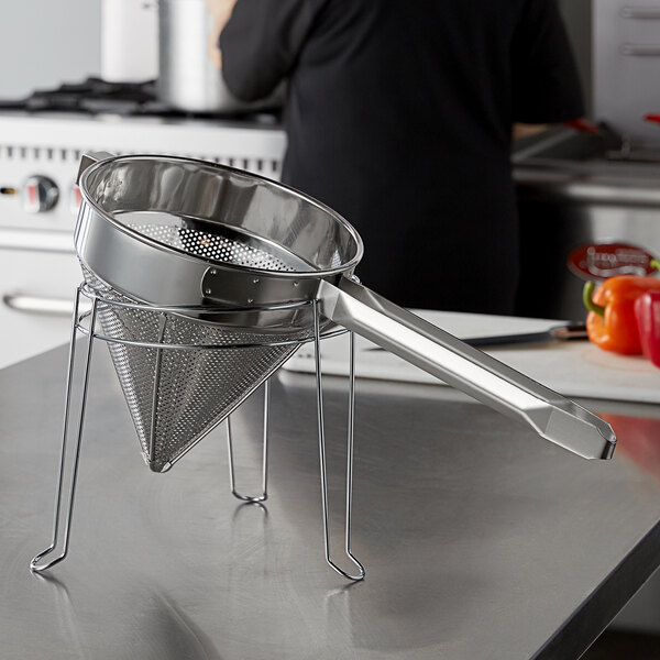 A stainless steel Choice strainer stand on a counter with a metal strainer in it.