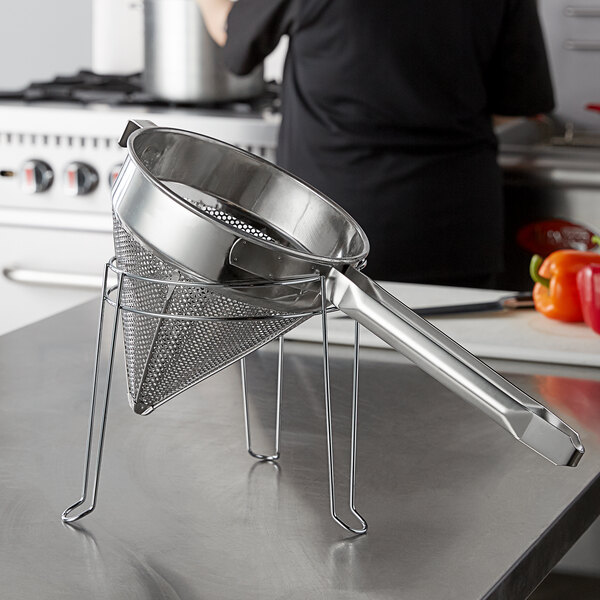 A Choice stainless steel strainer and stand set on a counter.
