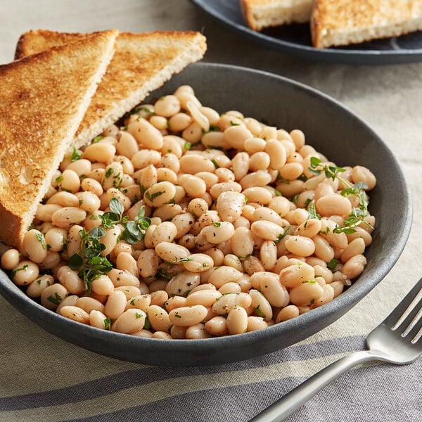 A bowl of Bella Vista Great Northern beans with toast on a white background with a fork.