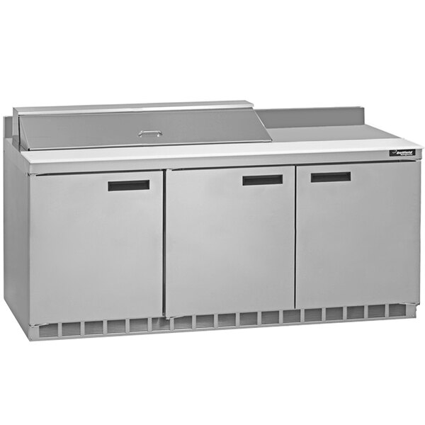 A stainless steel Delfield commercial refrigerator with three doors and a white surface.