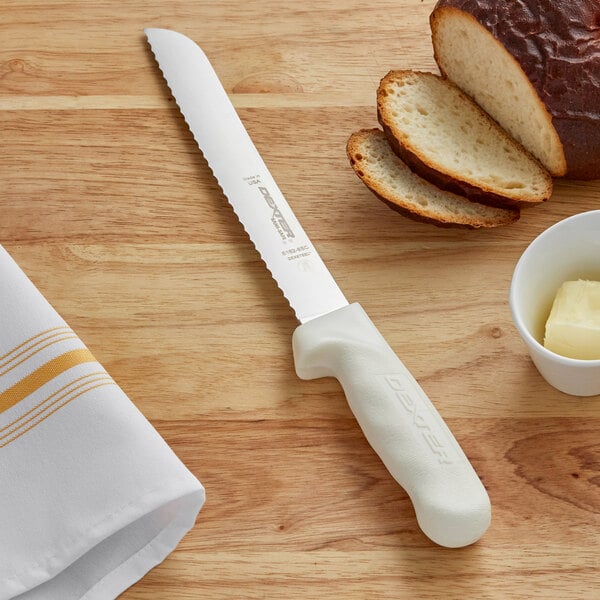 A Dexter-Russell white scalloped bread knife next to a loaf of bread.