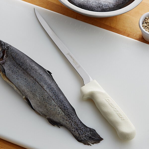 A Dexter-Russell Sani-Safe fillet knife cutting a fish on a cutting board.