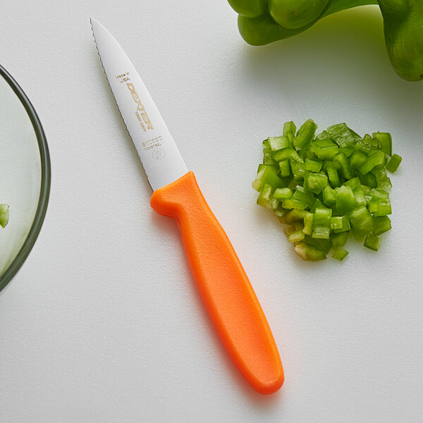 A Dexter-Russell Sani-Safe paring knife with an orange handle next to chopped green peppers.