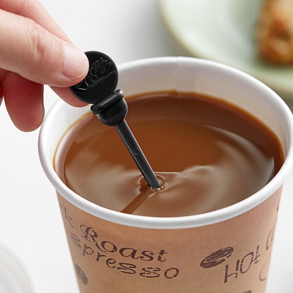 A hand using a Royal Paper black plastic stirrer in a cup of coffee.