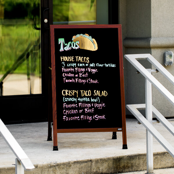 An Aarco cherry A-frame sign board with black marker board on the steps of a building with a chalkboard menu.