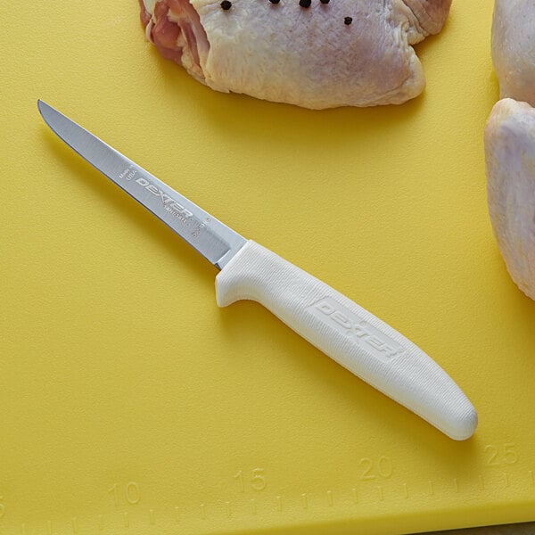 A Dexter-Russell boning knife on a cutting board with chicken.