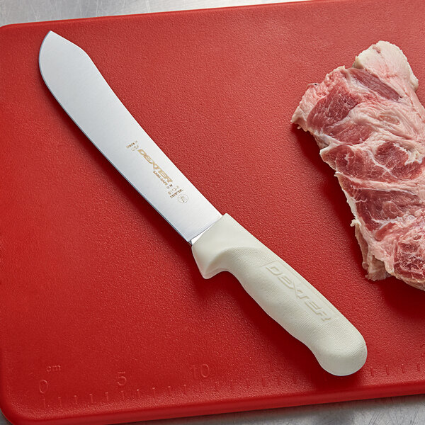 A Dexter-Russell butcher knife on a cutting board with meat.