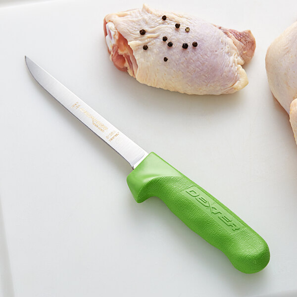 A Dexter-Russell Sani-Safe narrow boning knife with a green handle next to a piece of meat.