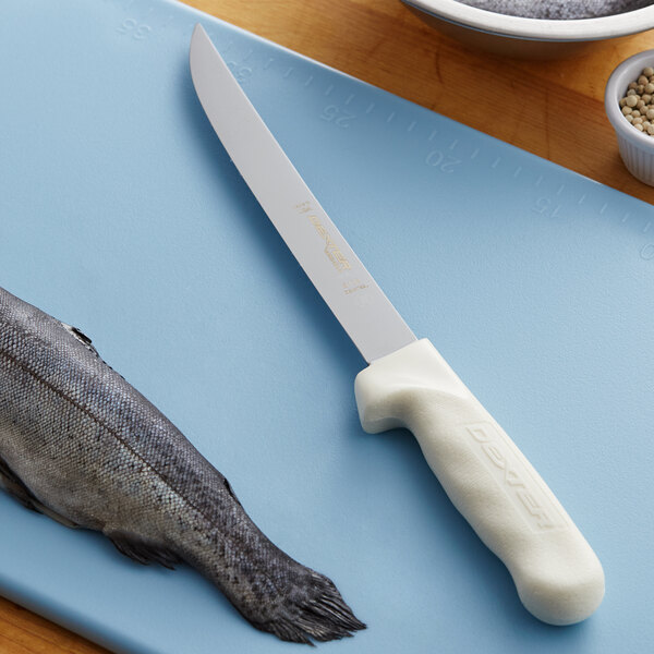A Dexter-Russell Sani-Safe fillet knife with a white handle next to a fish on a cutting board.