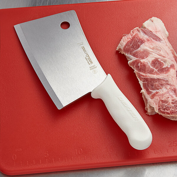 A Dexter-Russell meat cleaver on a cutting board next to meat.