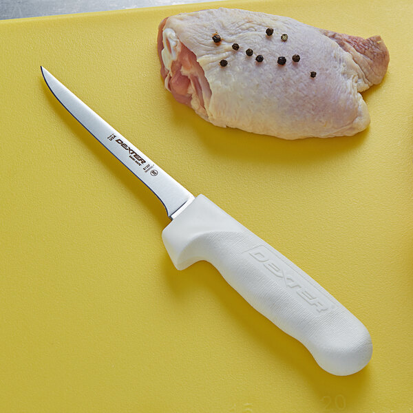 A Dexter-Russell Sani-Safe boning knife cutting a raw chicken breast.