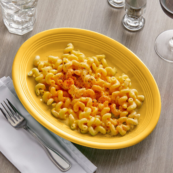 A Tuxton saffron oval china platter with macaroni and cheese on it, with a fork next to it.