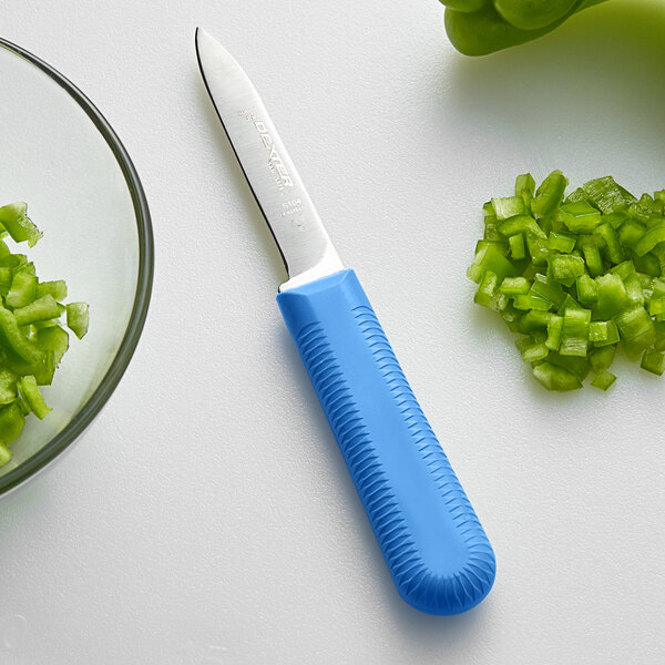 A Dexter-Russell Sani-Safe paring knife next to chopped green peppers.