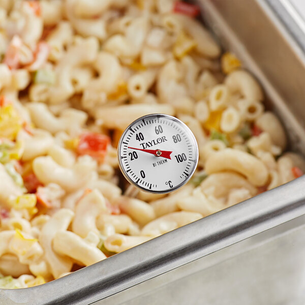 A Taylor pocket probe thermometer in a pan of macaroni and cheese.