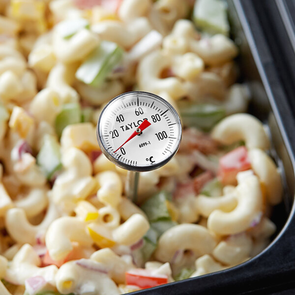 A Taylor pocket probe thermometer in a bowl of macaroni and cheese.