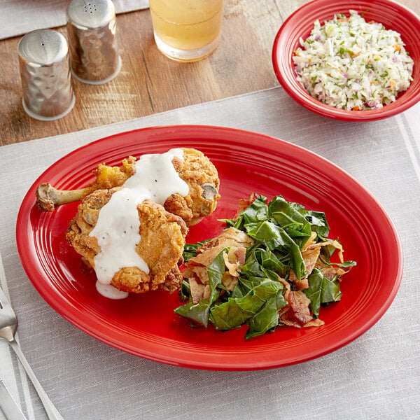 An Acopa Capri oval stoneware platter with fried chicken and a side salad on a table.