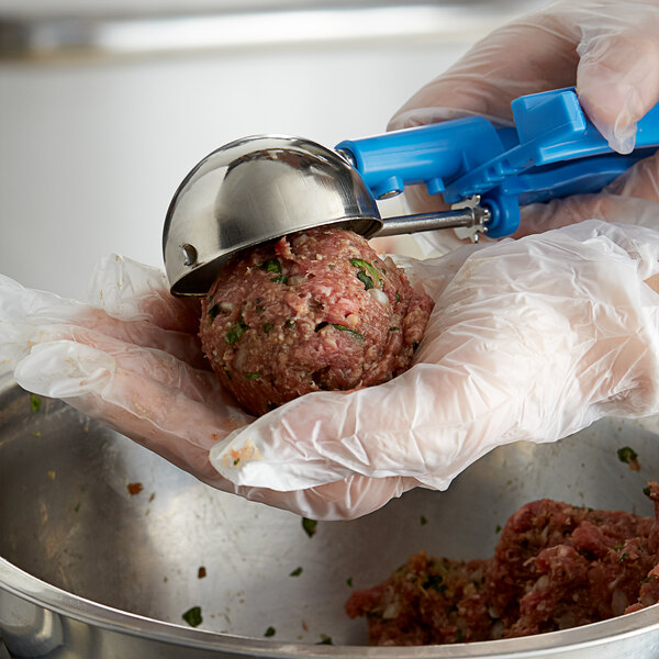 A gloved hand uses a Thunder Group Blue EZ Grip Disher to scoop a ball of meat.