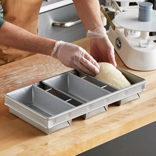 A person using a Baker's Mark aluminized steel bread loaf pan to make bread.