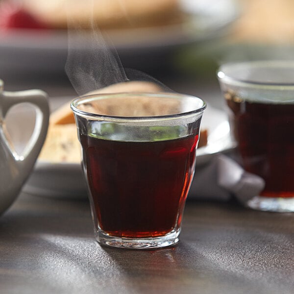 A Duralex Picardie glass filled with hot tea on a table.