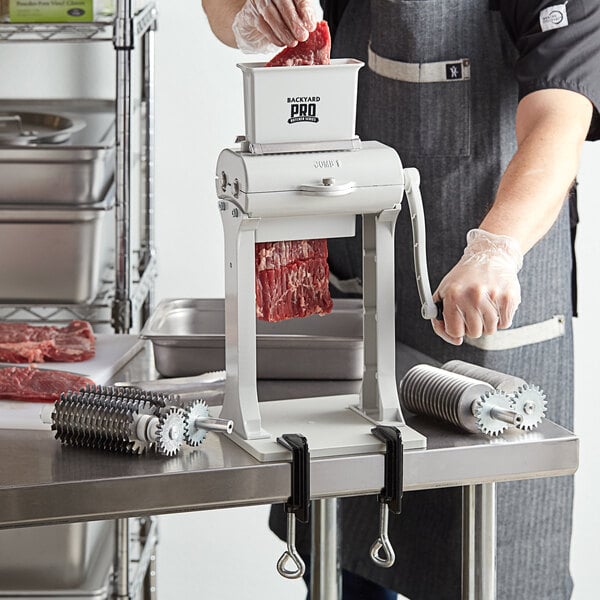 A man in an apron using a Backyard Pro meat tenderizer with jerky slicer blade set.