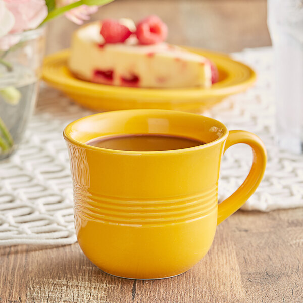 An Acopa mango orange stoneware cup filled with a drink on a table.