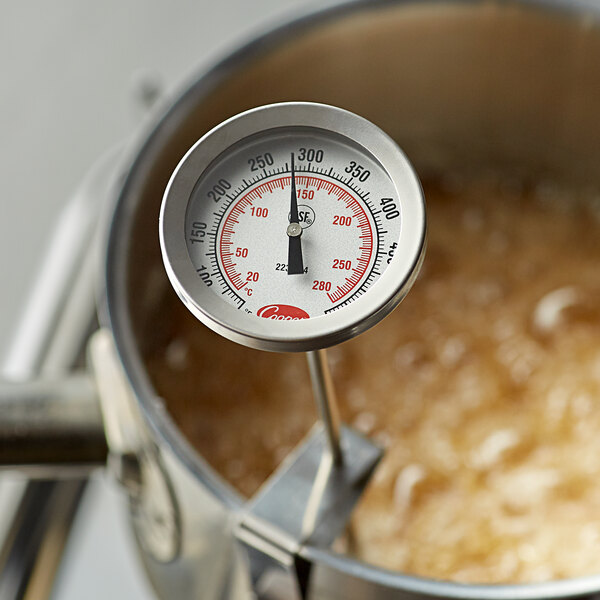 A Cooper-Atkins instant read probe thermometer in a pot of boiling liquid.