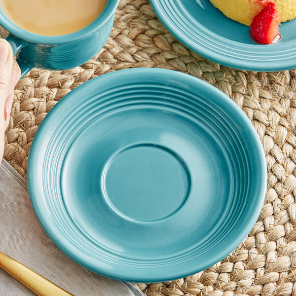 A Caribbean turquoise Acopa Capri stoneware saucer with a blue mug and a plate of strawberries and cake.