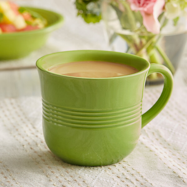A green Acopa Capri stoneware cup with a drink in it.
