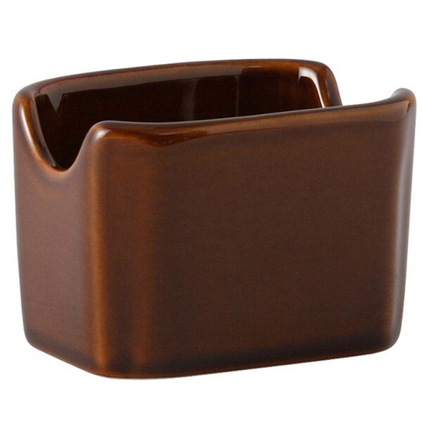 A brown ceramic Tuxton sugar packet holder with a curved edge.