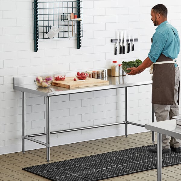 A man standing in a professional kitchen at a Regency stainless steel work table.