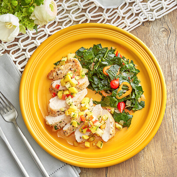 An Acopa Capri mango orange stoneware plate with chicken and pineapple salsa on a table.