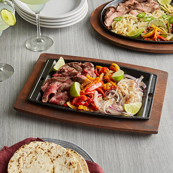 A Valor cast iron fajita skillet with food on a wood surface.