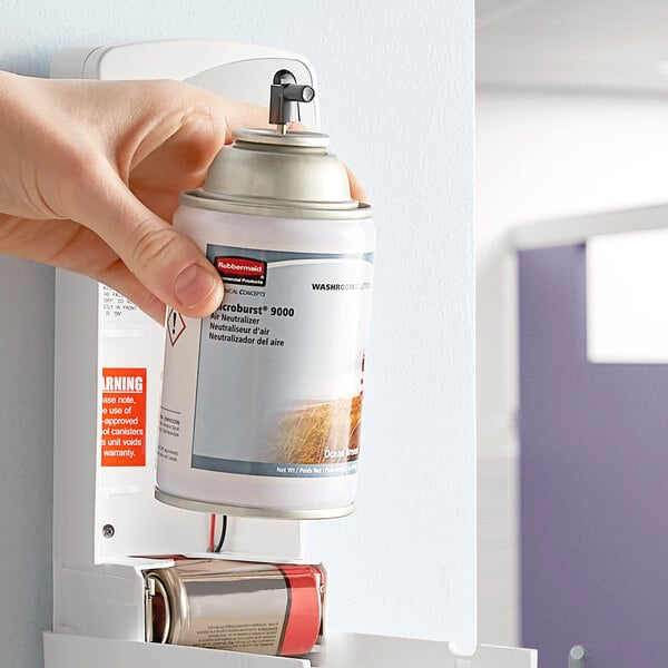 A person holding a Rubbermaid Microburst 9000 Ocean Breeze metered aerosol air freshener refill can.