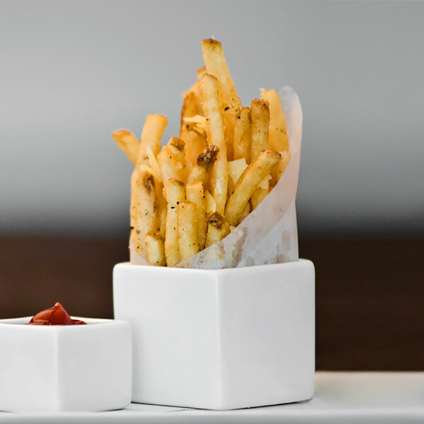 French fries in a Front of the House white square porcelain ramekin with ketchup.