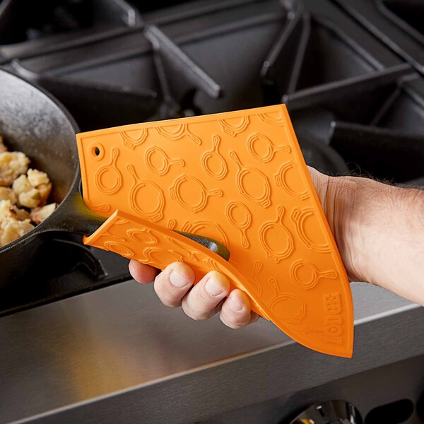 An orange Lodge silicone trivet with a skillet pattern.