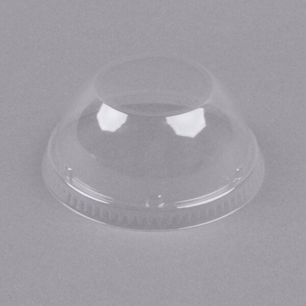 A clear plastic dome lid on a gray surface.