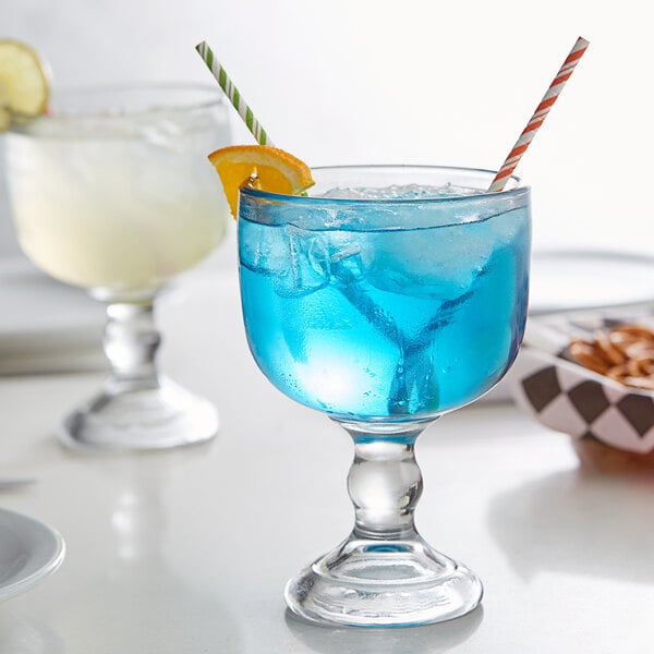 An Anchor Hocking schooner glass with blue liquid and a straw.
