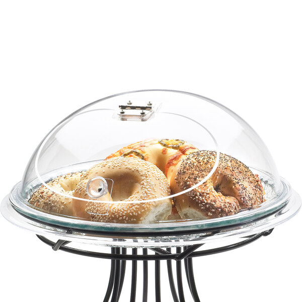 A Cal-Mil glass tray cover with a bagel with sesame seeds on it.