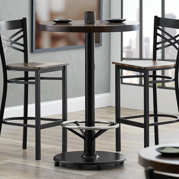 A Lancaster Table & Seating cast iron bar height table base with a foot rest and table equalizers.