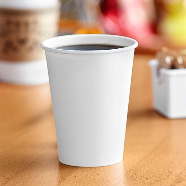 A Solo white paper hot cup on a table full of coffee.