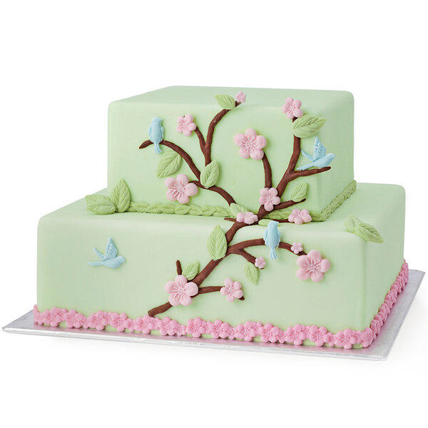 A white cake with flowers and birds on it made using the Wilton Nature Designs silicone mold.