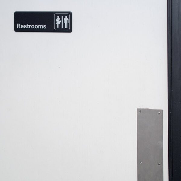 A bathroom door with a black and white sign that reads "Restrooms" by Thunder Group.