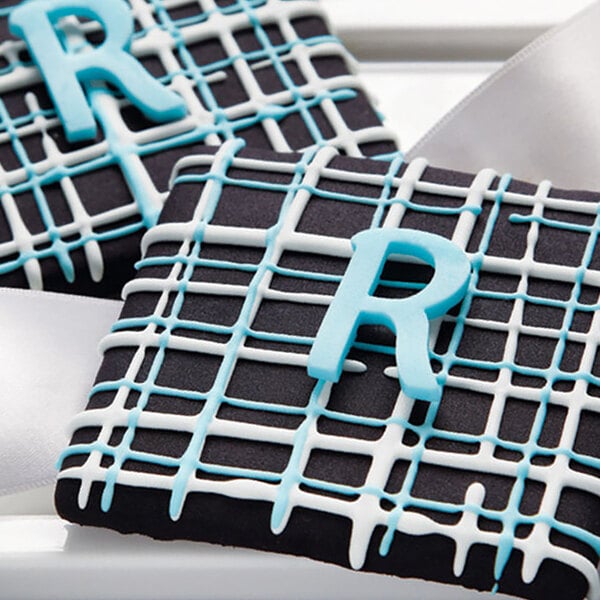 Two black and white cookies with blue and white icing, each with a blue letter r.