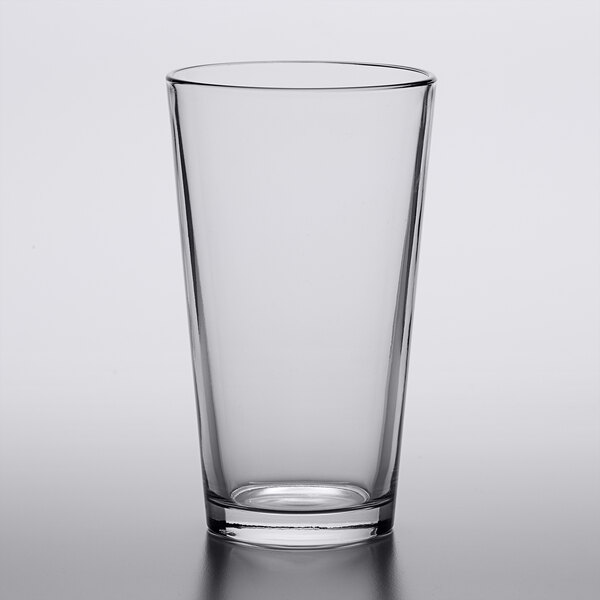 An Arcoroc clear mixing glass on a white surface.